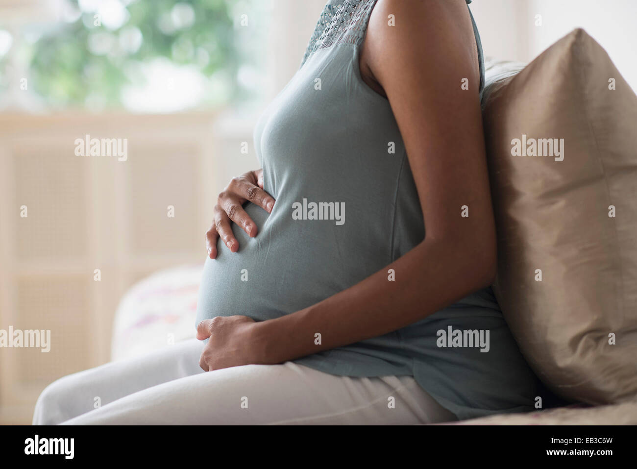 Africana incinta madre americana mentre tiene il suo stomaco Foto Stock