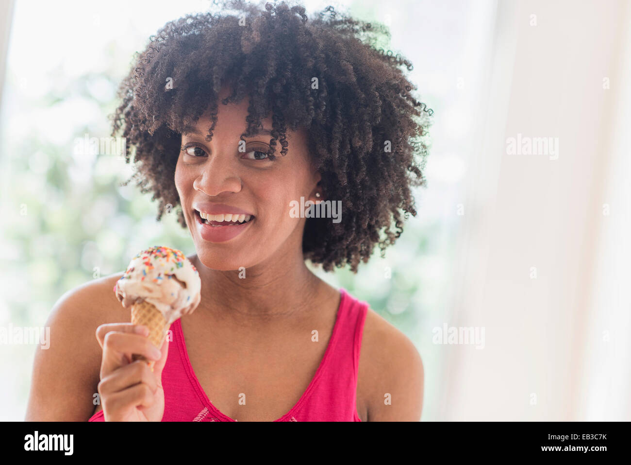 African American donna mangiare cono gelato Foto Stock