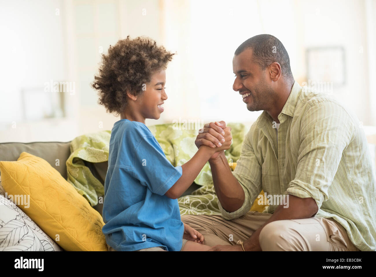 Padre e figlio arm wrestling nel soggiorno Foto Stock