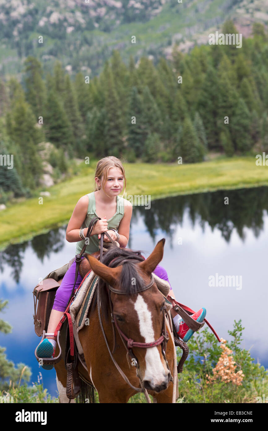 Ragazza caucasica a cavallo nel vicino lago Foto Stock