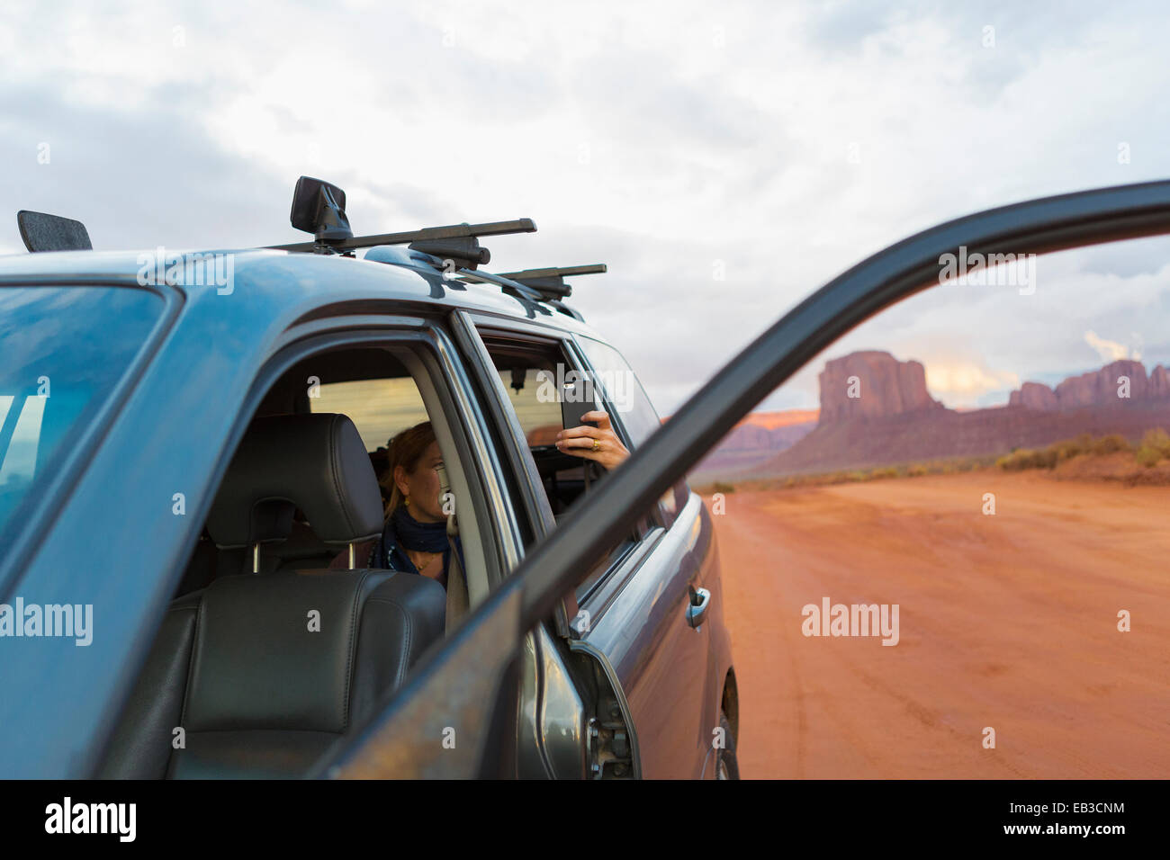 Ragazza caucasica tenendo cellulare fotografia da auto, Monument Valley, Utah, Stati Uniti Foto Stock