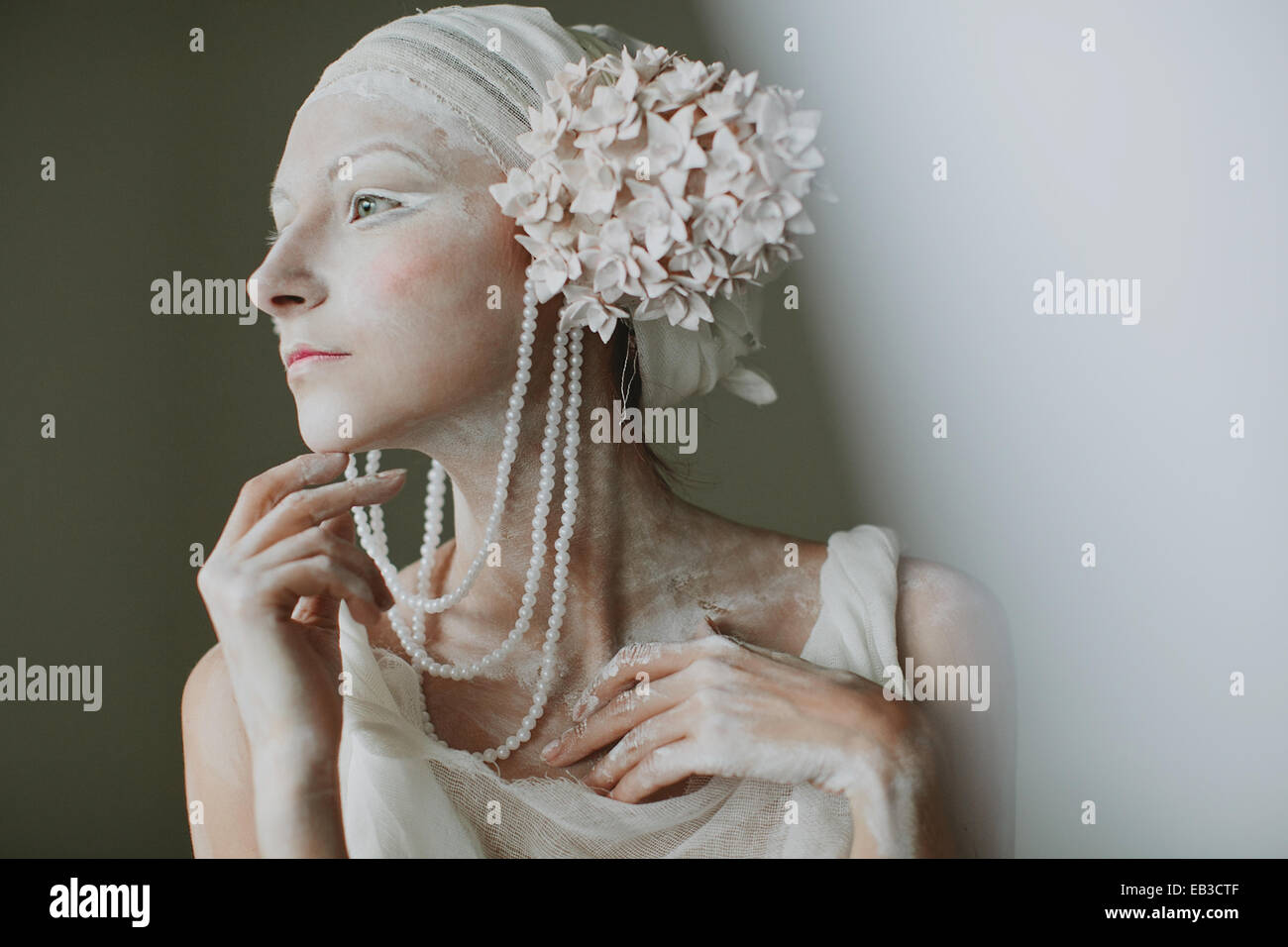 Ritratto di giovane donna che indossa il make up, greasepaint, perline e decorazioni di orecchio che assomigliano a infiorescenza Foto Stock