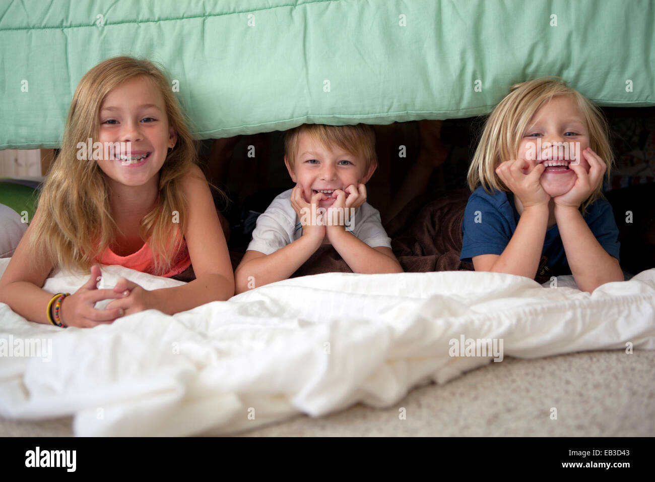 Bambini caucasici posa sotto il letto Foto Stock