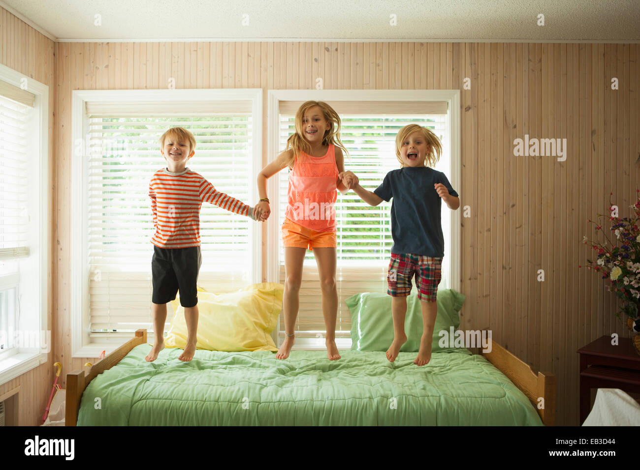 Bambini caucasici saltando sul letto Foto Stock