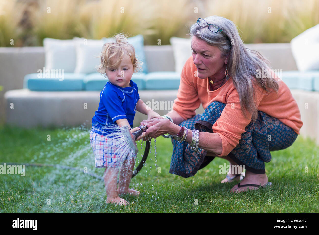 Nonna caucasica e baby nipote prato irrigazione con tubo flessibile Foto Stock