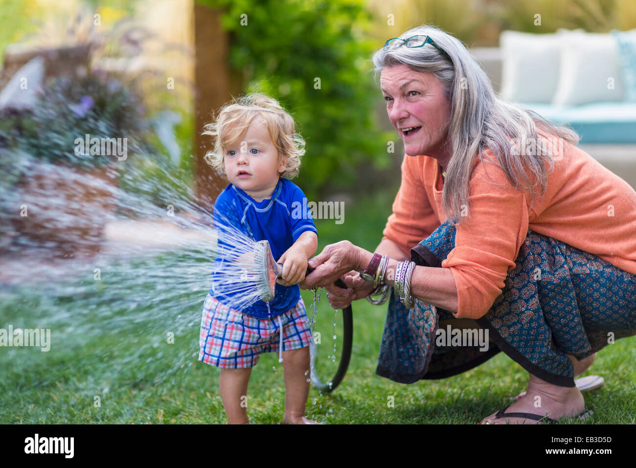 Nonna caucasica e baby nipote prato irrigazione con tubo flessibile Foto Stock
