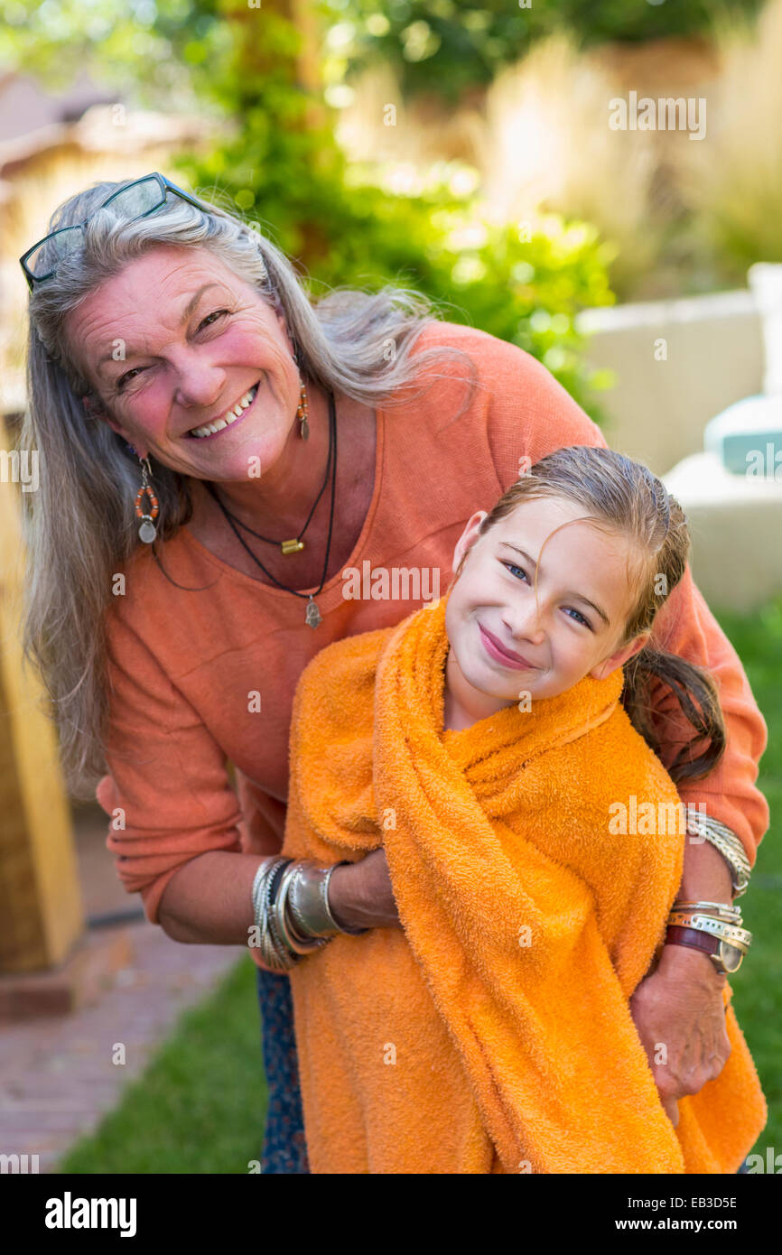 Nonna caucasica nipote di incarto in asciugamano in cortile Foto Stock