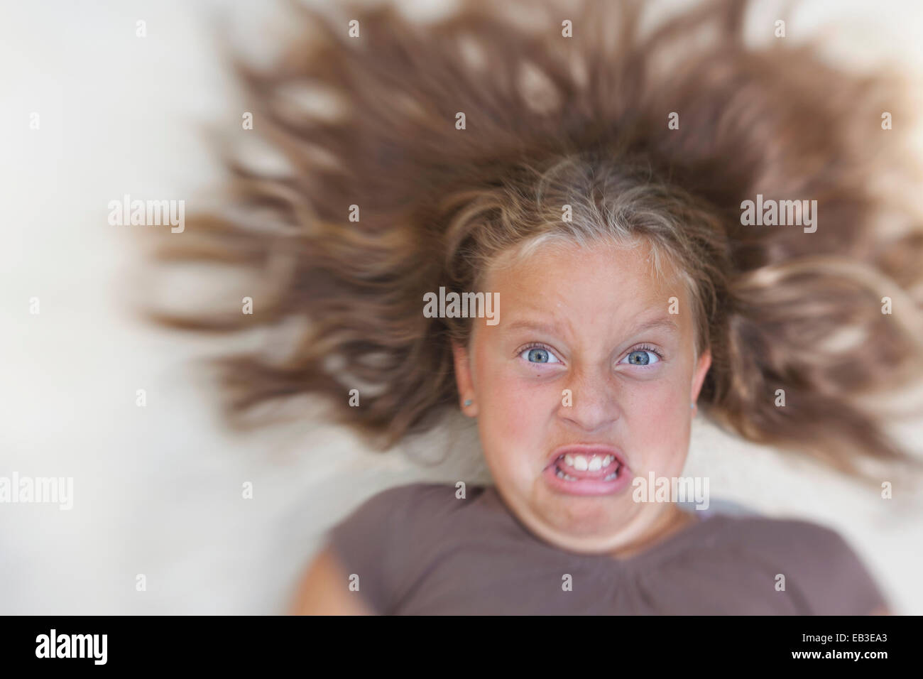 Ragazza con capelli disposti tirando facce divertenti Foto Stock