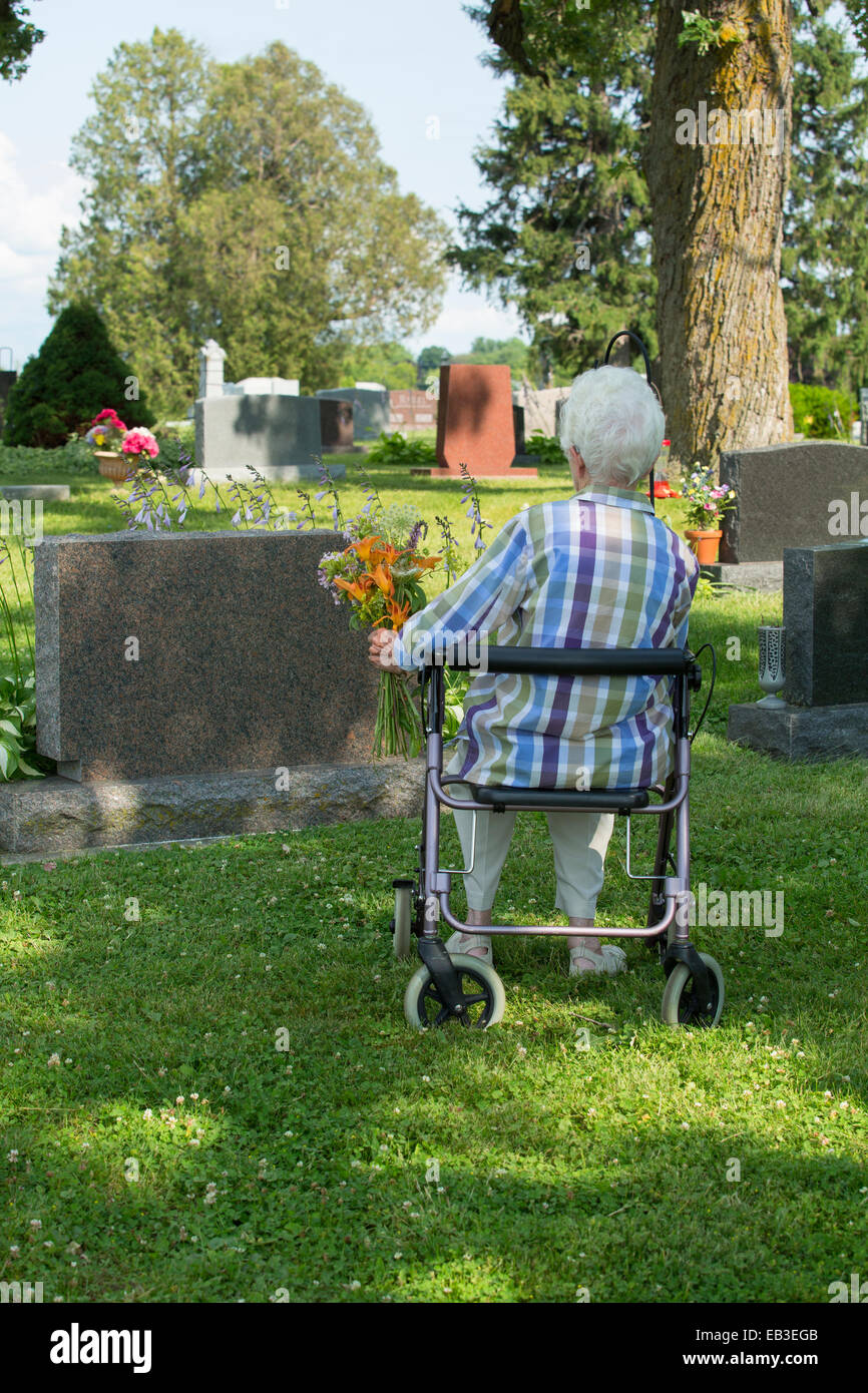 I vecchi donna caucasica visita tomba nel cimitero Foto Stock