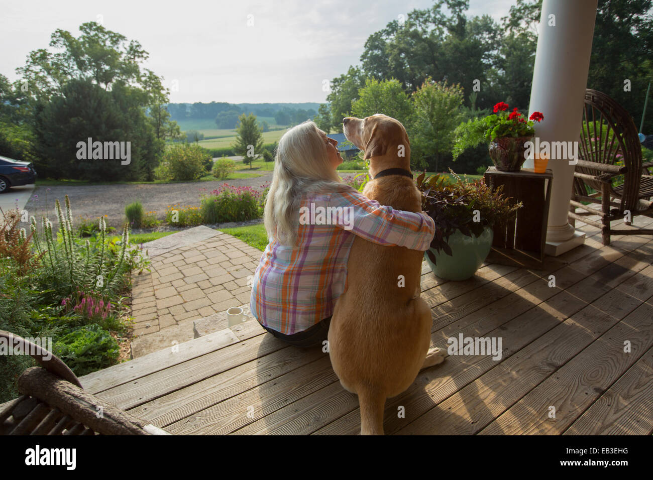 I vecchi donna caucasica petting cane sul portico anteriore Foto Stock