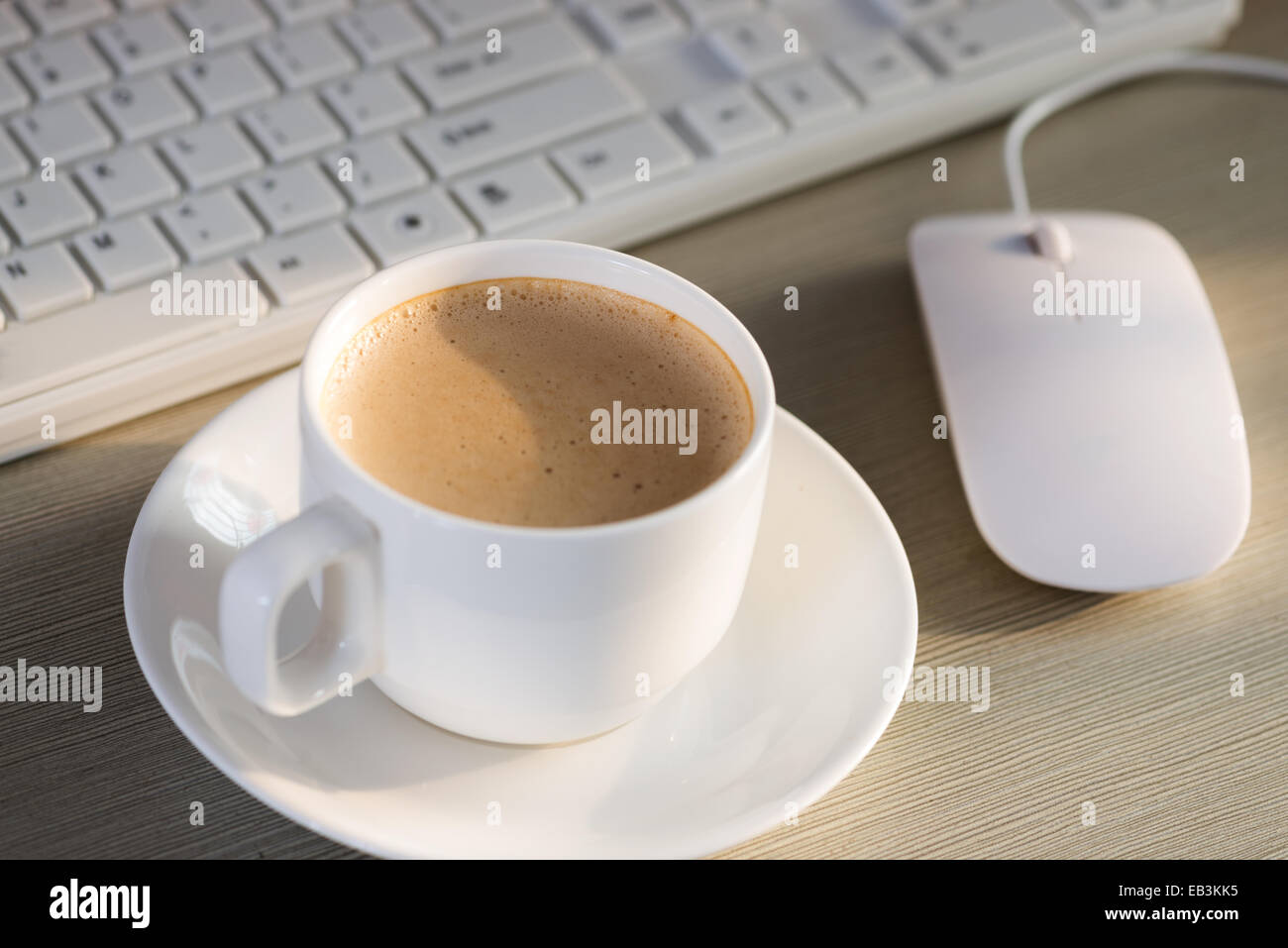Close-up del caffè, telefono cellulare, penne e una tazza di tastiera sul desktop Foto Stock