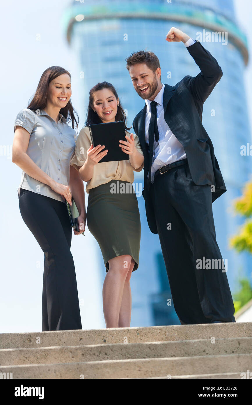 Il team Aziende di successo di uomo e di donna, imprenditore imprenditrice, celebrando e utilizzando un computer tablet in una città moderna Foto Stock