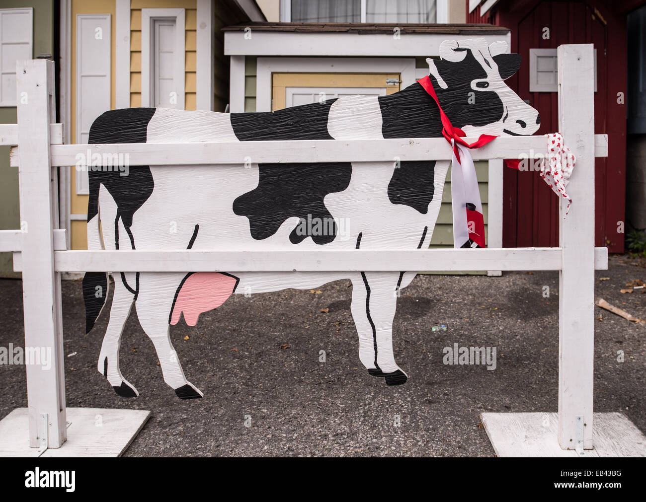 Un bianco e nero vacca Holstein ornamento dietro un bianco cancellata. Foto Stock