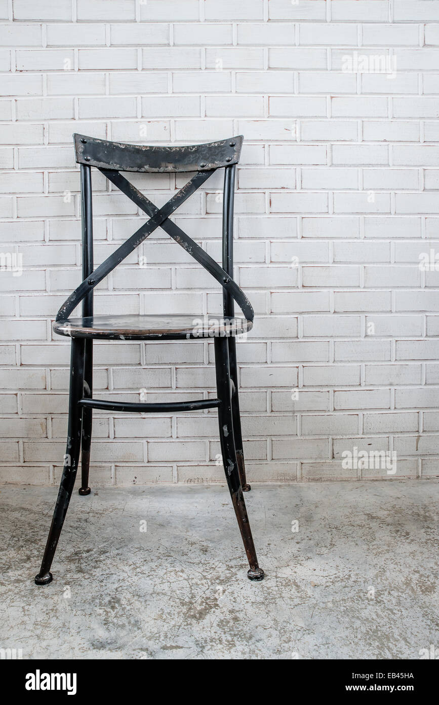 Classica sedia in ferro con il bianco muro di mattoni Foto Stock