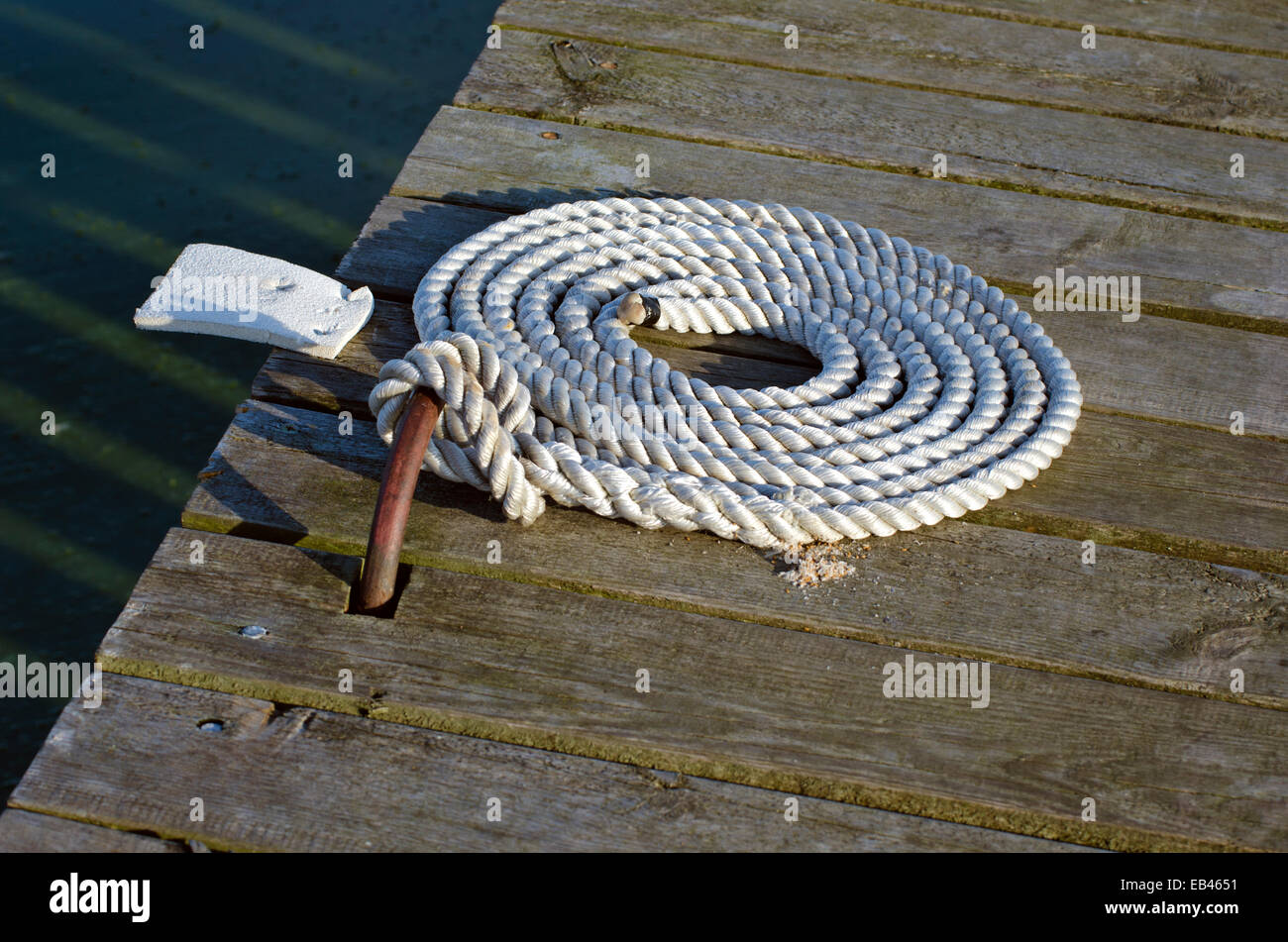 La cima di ormeggio con estremità annodate legato sul molo in legno/ Nautico corda di ormeggio Foto Stock