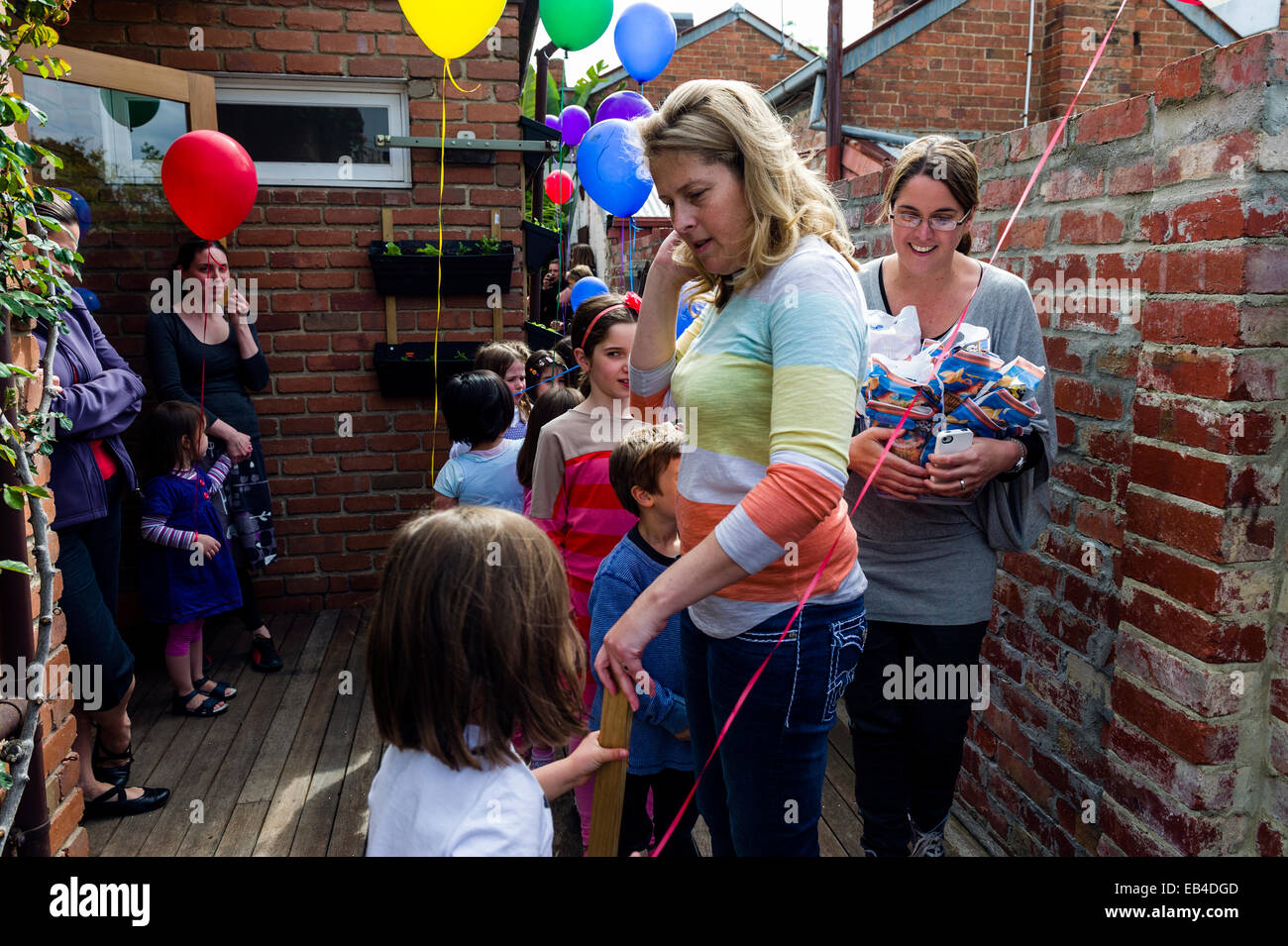 Una madre ad una festa di compleanno controllando i figli a mano il trattamento sacchi. Foto Stock