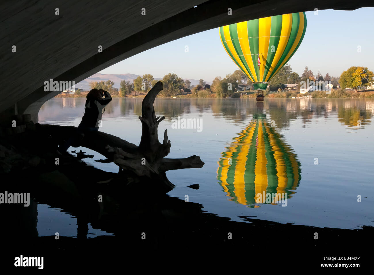 Visto da sotto un ponte, una mongolfiera dal palloncino Prosser Rally galleggianti appena al di sopra del fiume Yakima come un fotografo guarda a. Foto Stock