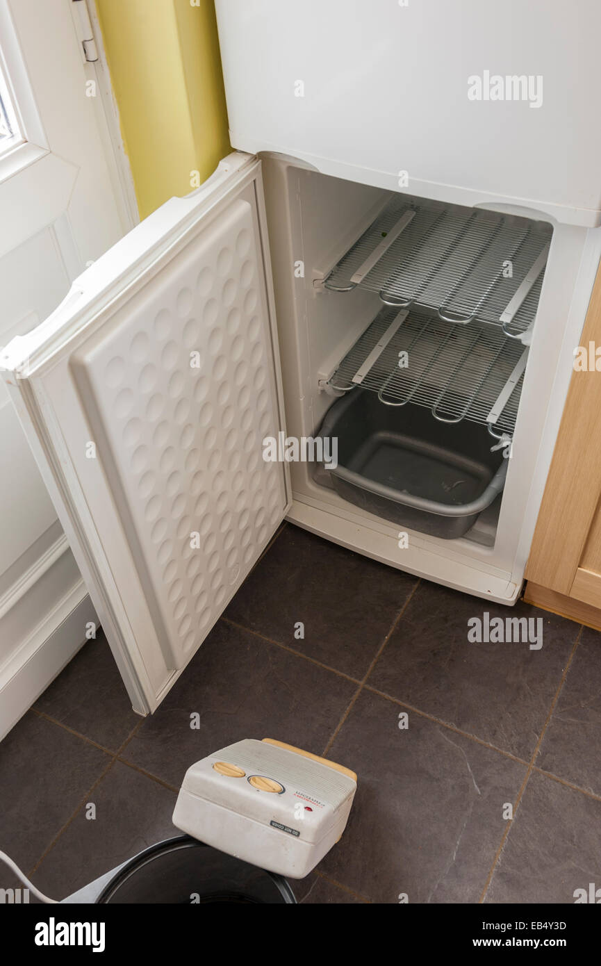 Sbrinare un congelatore con un riscaldatore Foto Stock