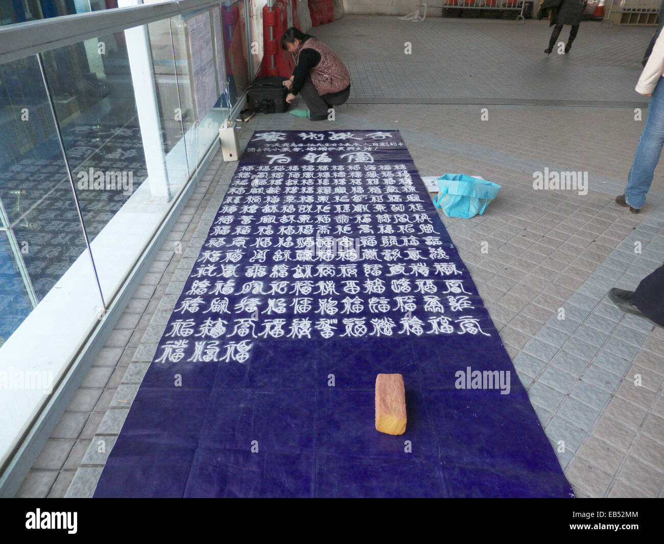 Cina continentale cinese unico madre scrittura calligrafia di sabbia sulla terra. Ella ha affermato che sua figlia ha bisogno di denaro per i medici tr Foto Stock