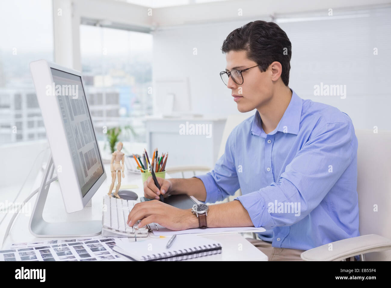 Editor foto al lavoro presso la sua scrivania Foto Stock
