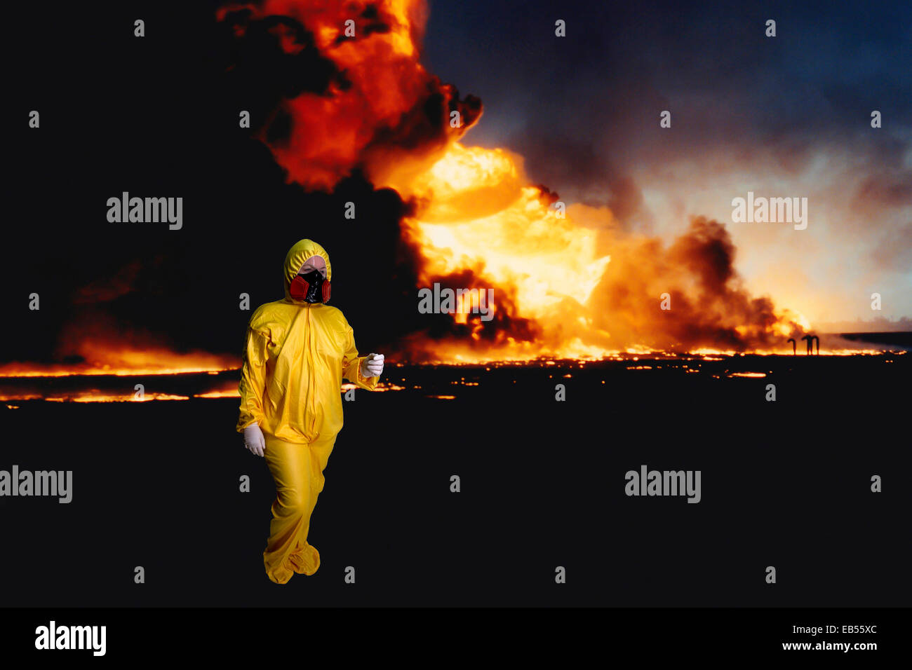 La donna in un hazmat suit a piedi da un pozzo di petrolio fuoco Foto Stock