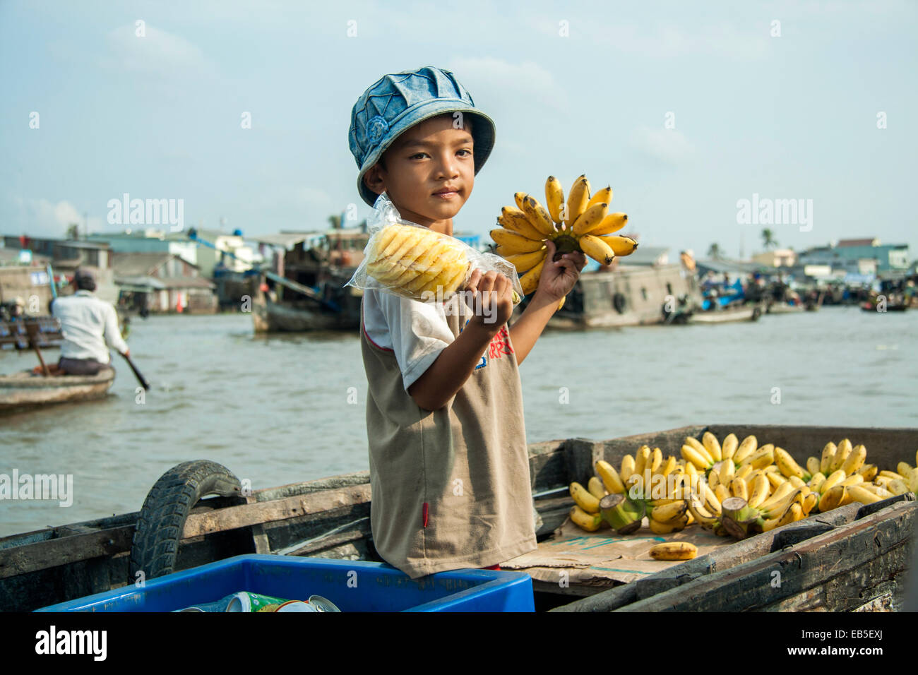 Giovane ragazzo cambogiano la vendita delle banane da una imbarcazione in un lago di mercato Foto Stock