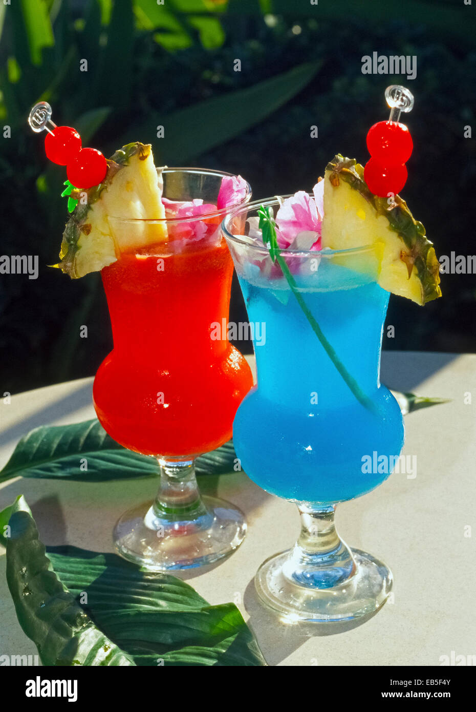 Fette di ananas, petali di fiori e ciliegie al maraschino decorare colorata e rinfrescante drink tropicale che sono popolari nelle isole Hawaii, Stati Uniti d'America. Foto Stock