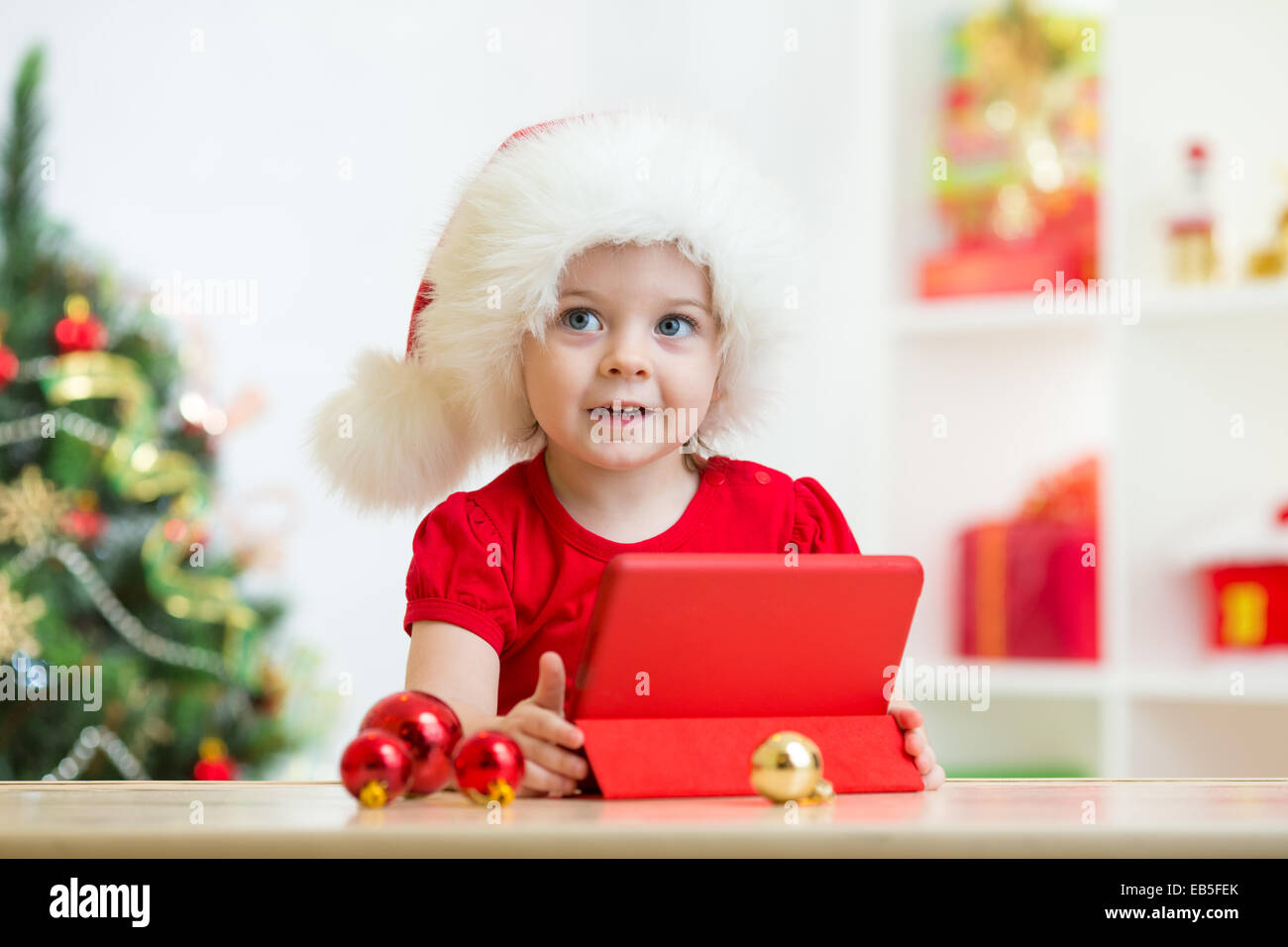 Il toddler ragazza nel cappello di Natale con i tablet pc Foto Stock