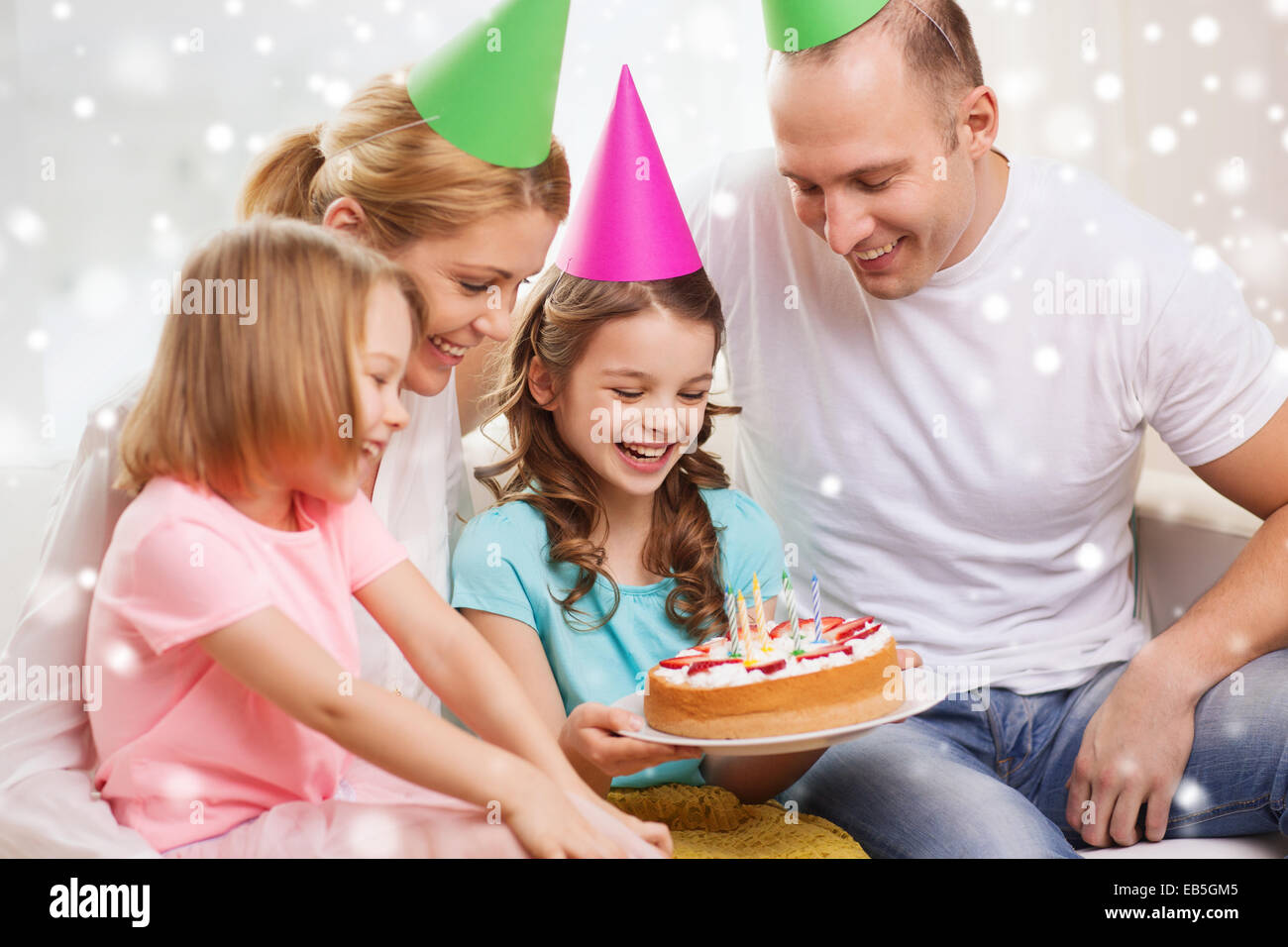 Felice famiglia con due bambini in party cappelli a casa Foto Stock
