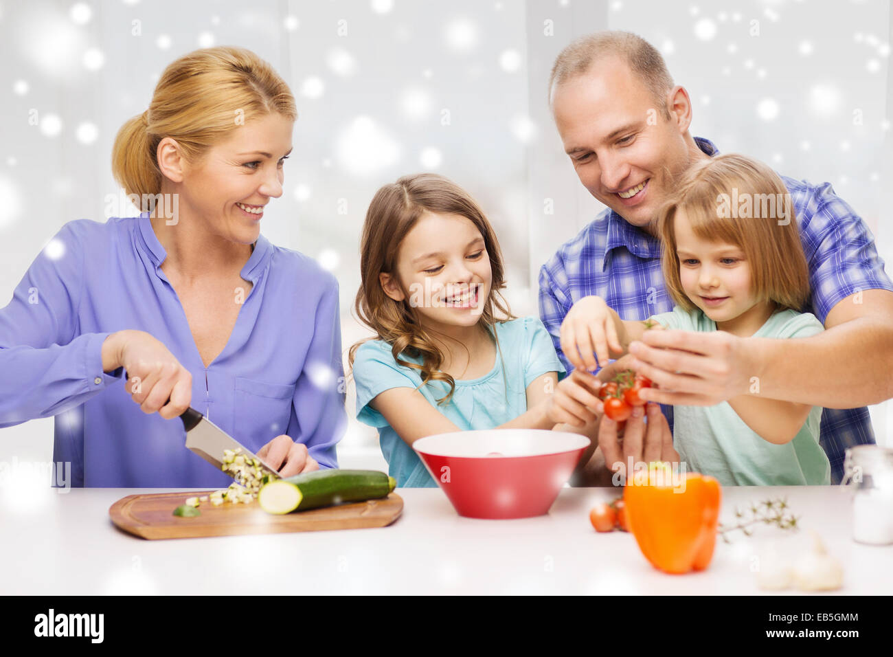 Felice famiglia con due bambini di preparare la cena a casa Foto Stock