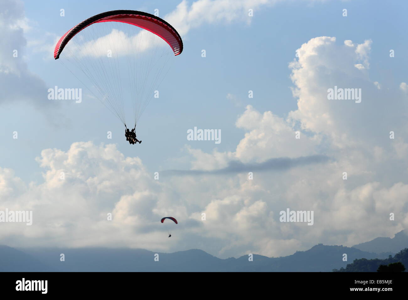 Parapendio fly i cieli Phewa tal-lago dopo il salto dal minor pendici della gamma Annapurnas-Himalayas-Pokhara. Foto Stock