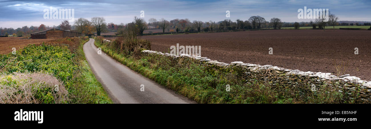 Una piccola strada di campagna che conduce a edifici agricoli nella periferia di Tetbury nel Gloucestershire. Foto Stock