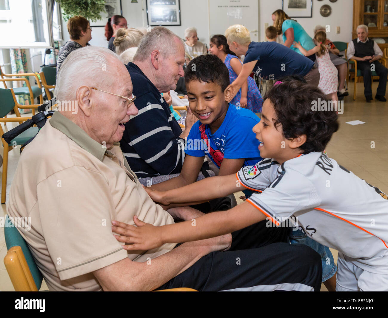 Due 6-year-old boys da un gruppo di asilo cercano il contatto a un 90-anno-vecchio senior in una casa di riposo Foto Stock