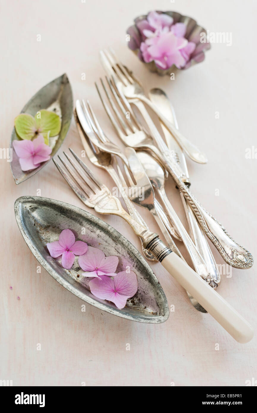 Vintage posate e le teglie con i fiori delle ortensie su una crema angosciate di legno verniciato board Foto Stock