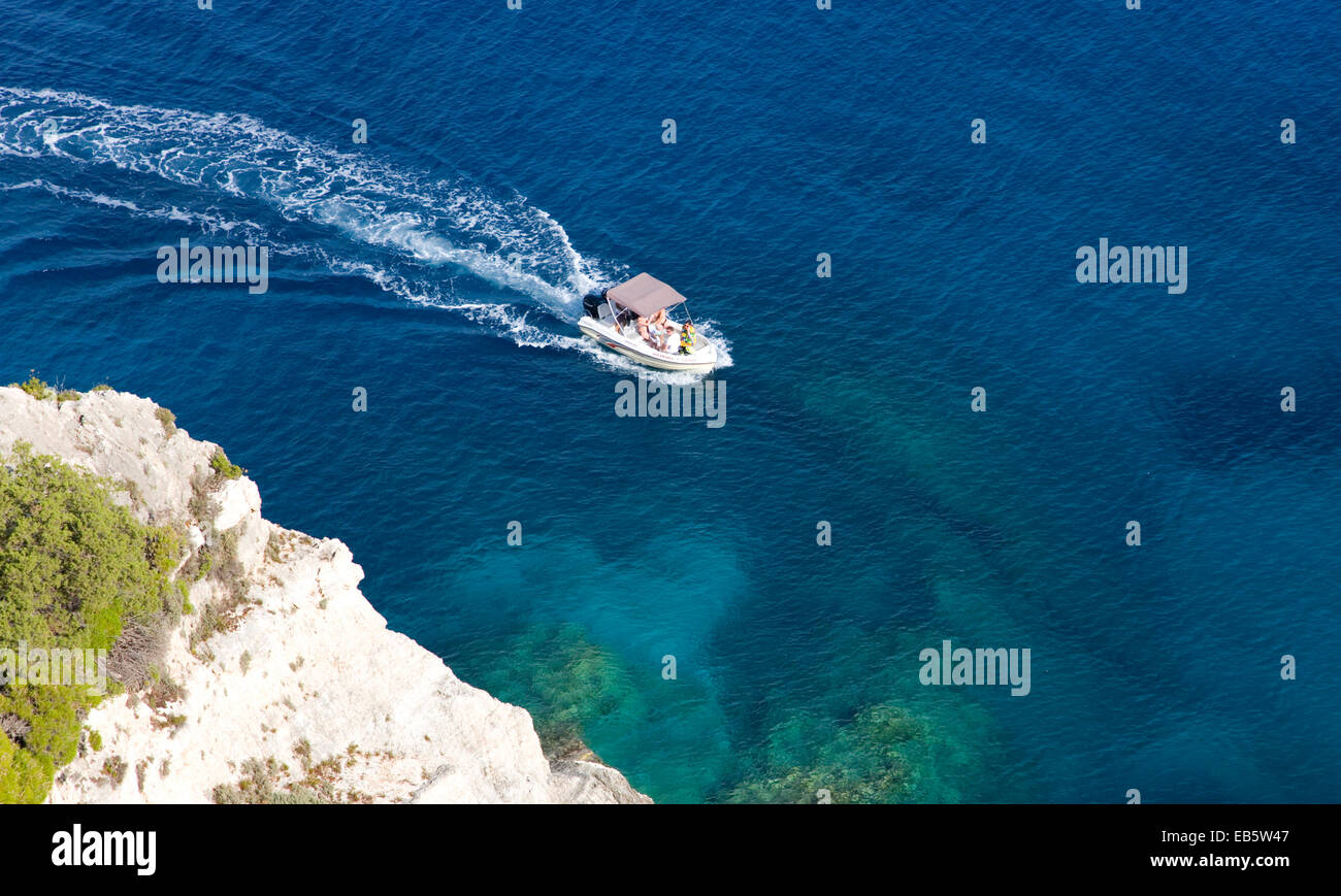 Korithi, Zante, Isole Ionie, Grecia. Piccola barca passando sotto le scogliere sopra le Grotte blu a Capo Skinari. Foto Stock