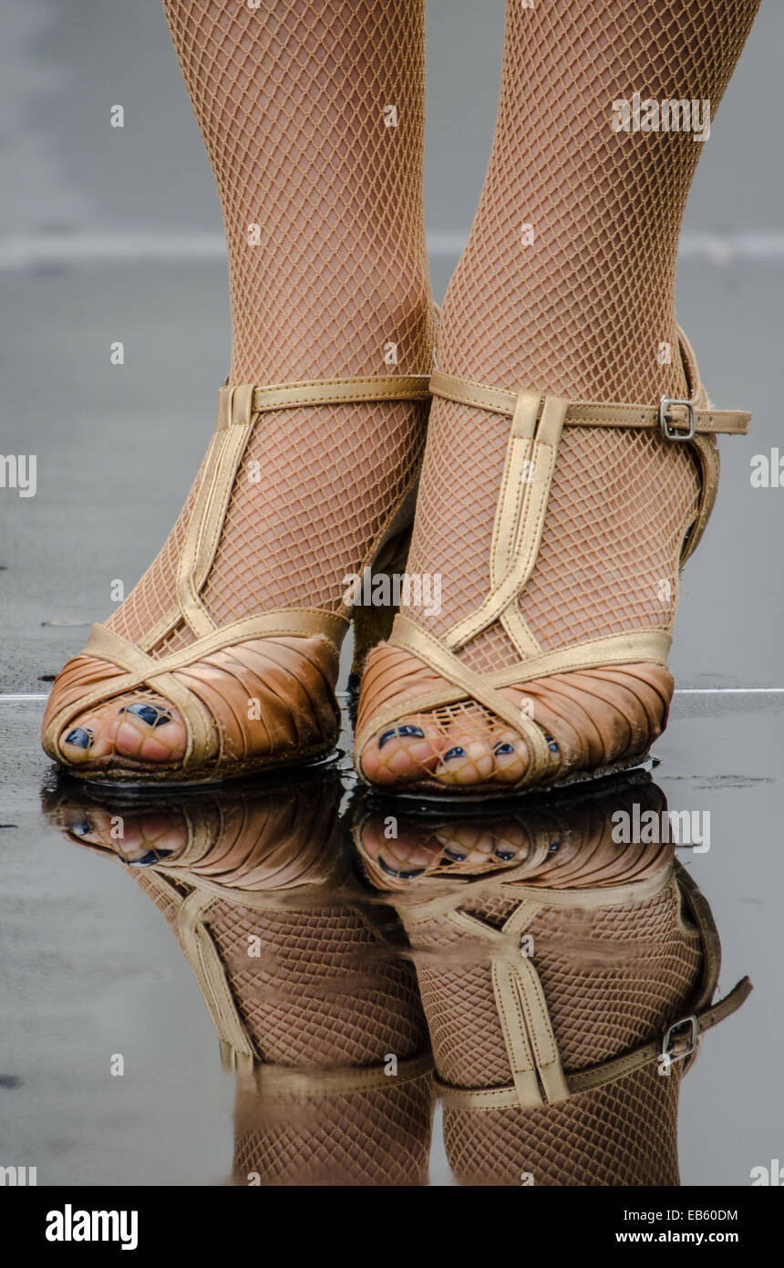 Tacchi alti sotto la pioggia. Femmina con Tutina in rete collant e scarpe strappy sul bagnato di un giorno di pioggia. La Riflessione Foto Stock