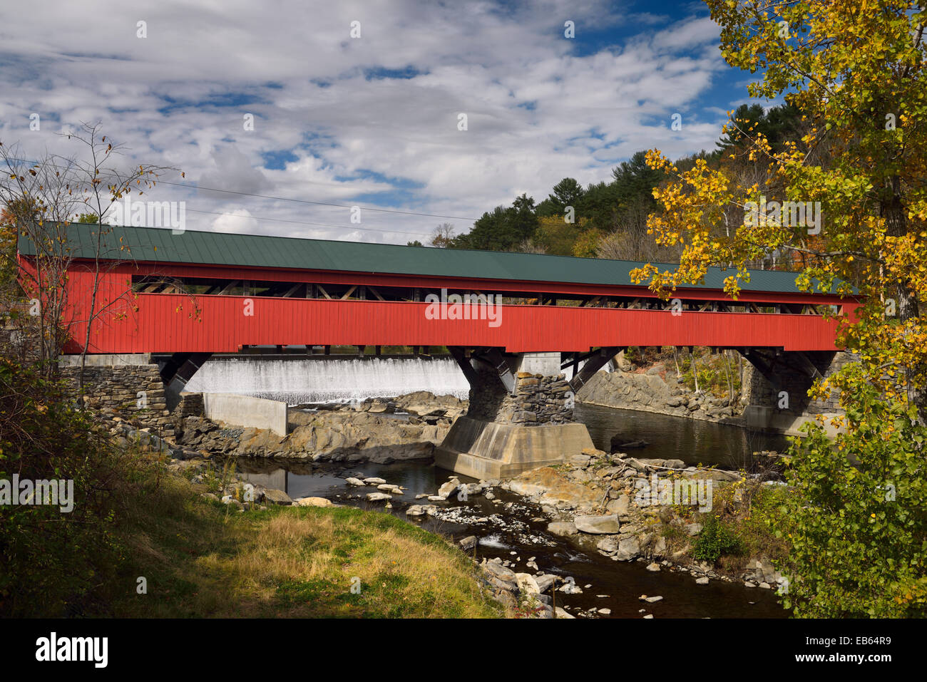 Diga idroelettrica rientra al rosso coperto di legno ponte sul fiume Ottauquechee in Taftsville Vermont USA in autunno Foto Stock