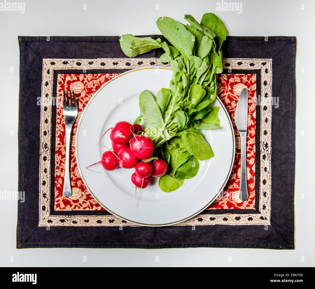 Crudo fresco ravanelli su una piastra bianca con una forchetta e un coltello Foto Stock