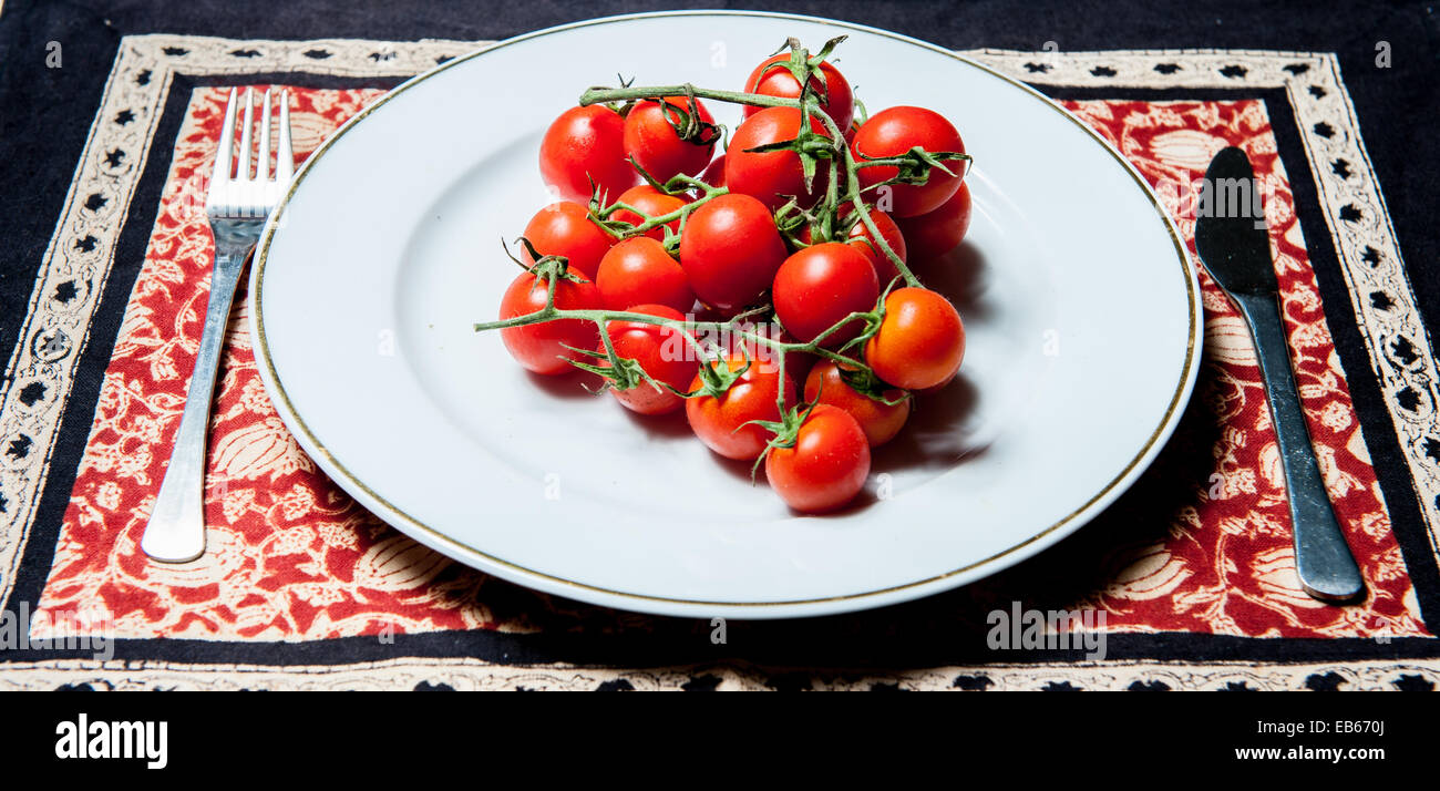 Crudo fresco di pomodori pachino classe su una piastra bianca con una forchetta e un coltello Foto Stock