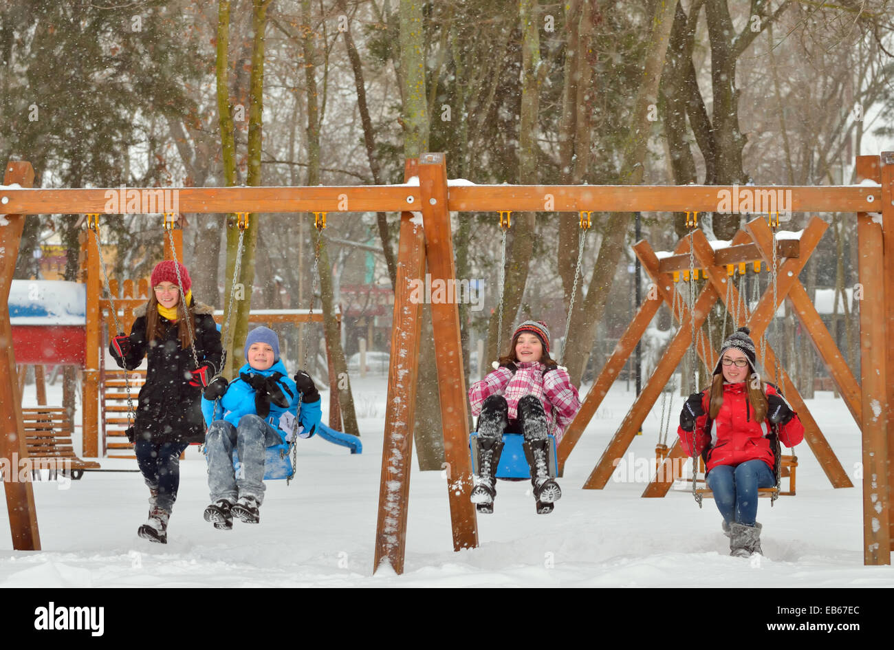 Happy amici seduti su altalena nel Parco in inverno Foto Stock
