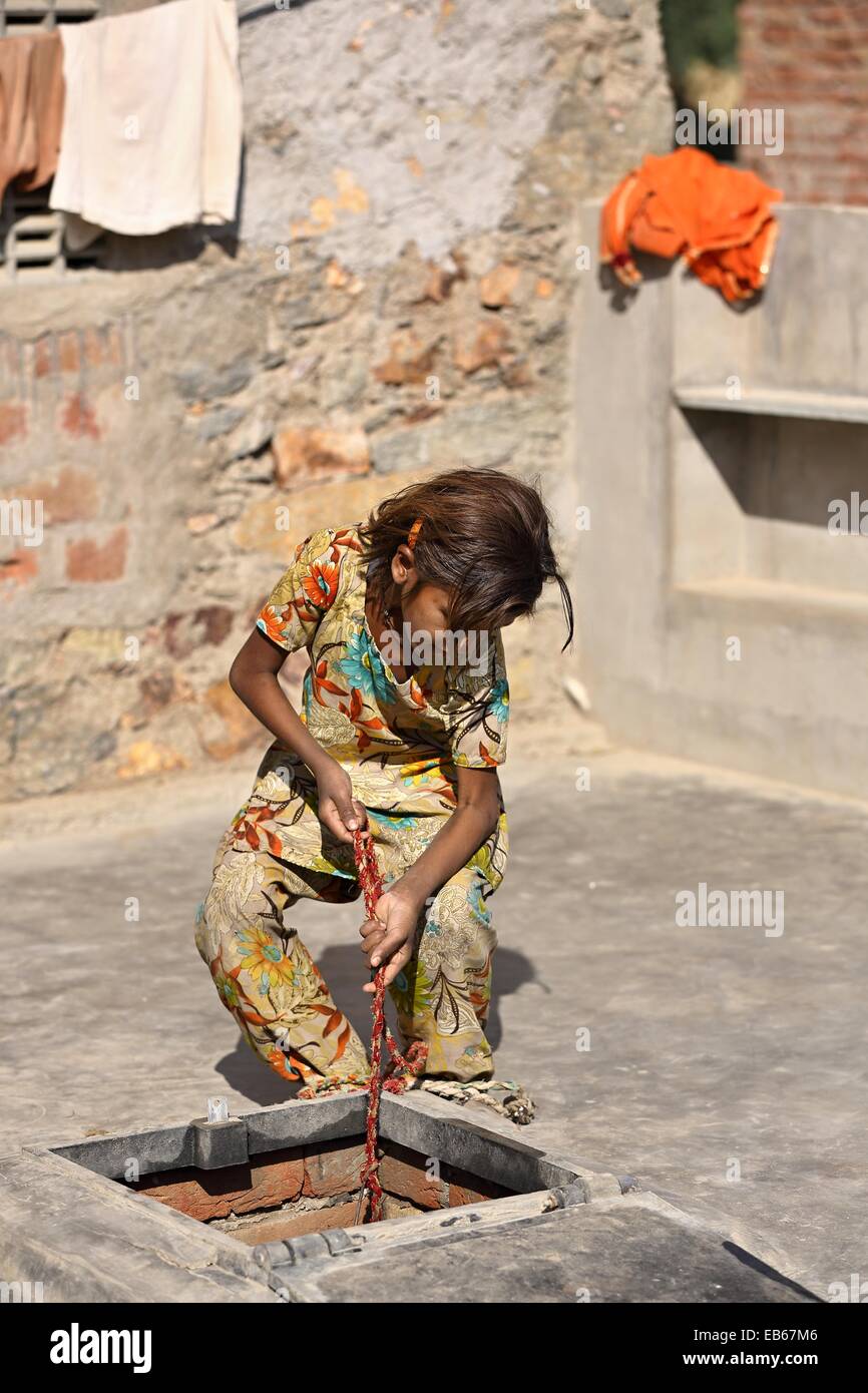 Giovane ragazza indiana il sollevamento di una pentola di acqua da una pioggia serbatoio acqua India Foto Stock