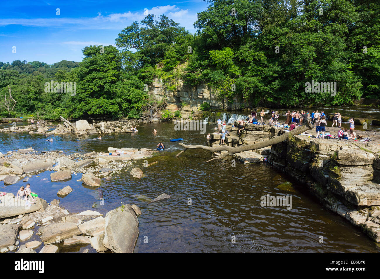 Folle di giovani persone che giocano in acqua, estate sul fiume Swale, Richmond, North Yorkshire, Inghilterra Foto Stock