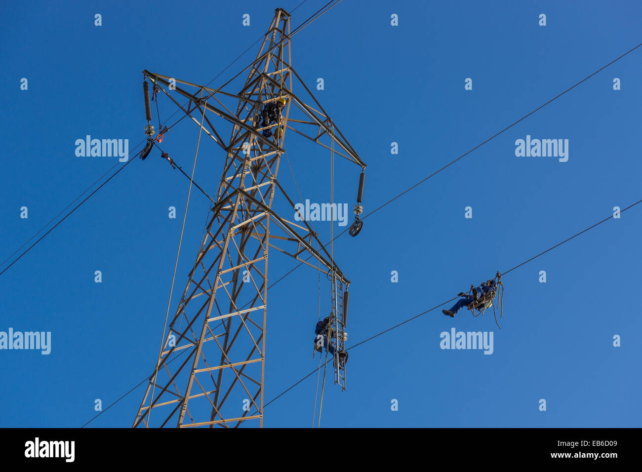 Operai di rinnovare i cavi ad alta tensione sul pilone dell'cielo blu andalusia MALAGA NATIONAL GRID PERICOLOSO LAVORO ALTAMENTE PAGATO Foto Stock