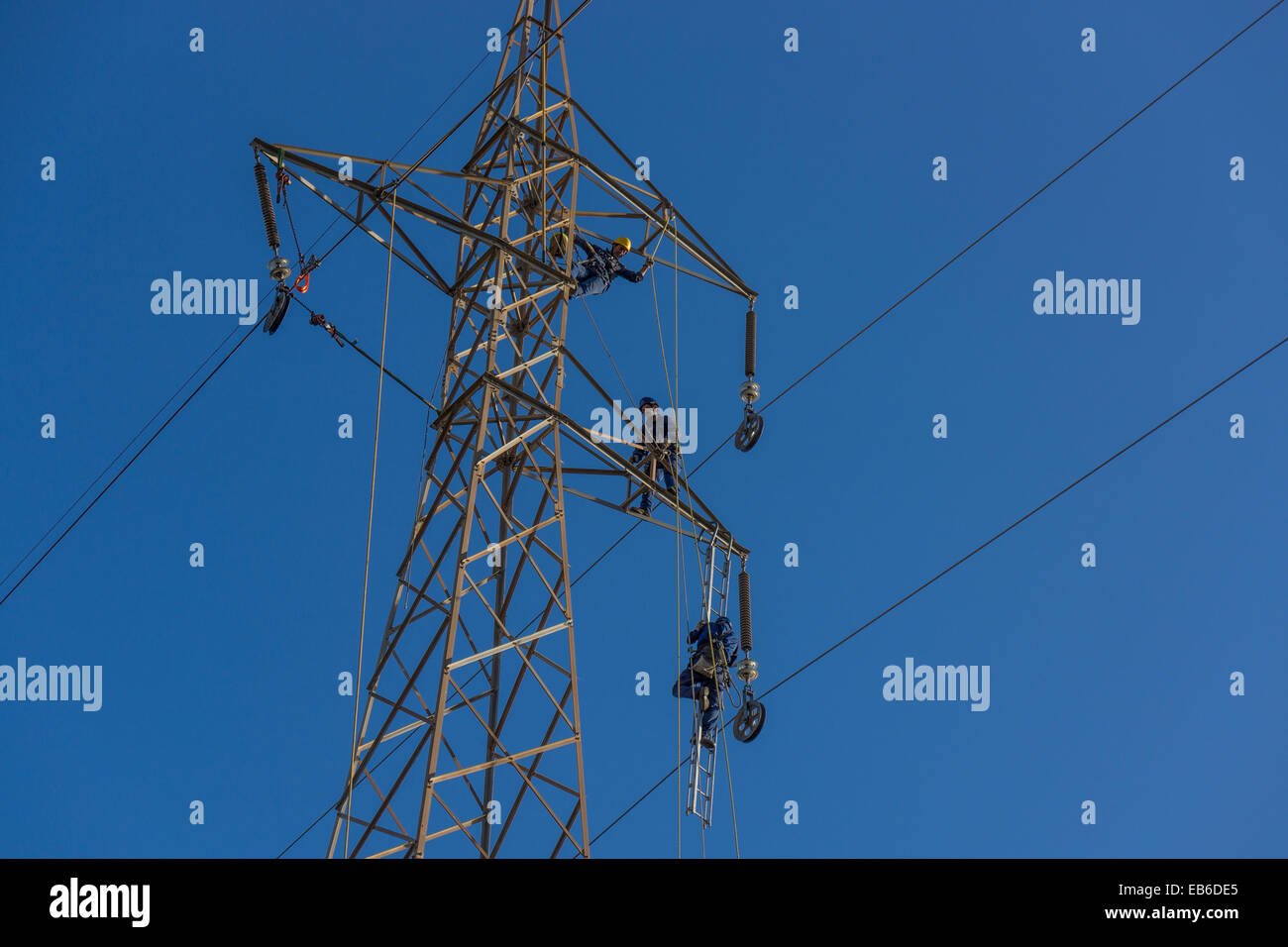 Operai di rinnovare i cavi ad alta tensione sul pilone dell'cielo blu andalusia MALAGA NATIONAL GRID PERICOLOSO LAVORO ALTAMENTE PAGATO Foto Stock
