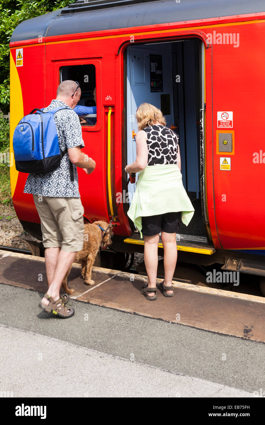 Un uomo, donna e cane a salire su un treno, Derbyshire, England, Regno Unito Foto Stock