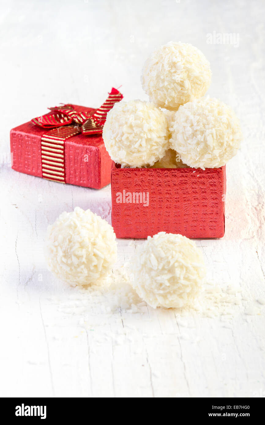 Snowball di cocco tartufi in confezione regalo su sfondo bianco. Disposizione dei cookie di noce di cocco in legno elegante sfondo. Foto Stock