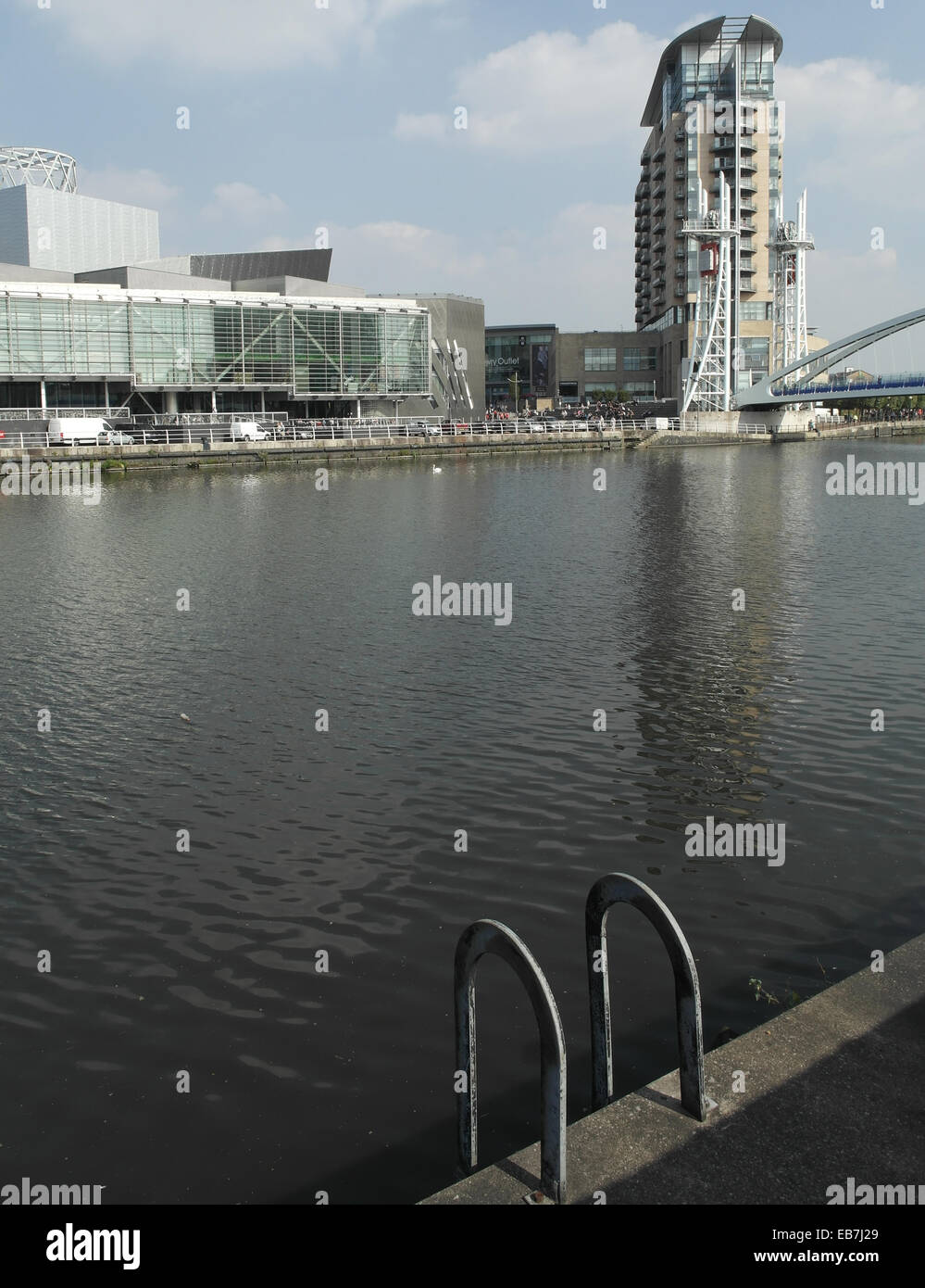 Ritratto Solare attraverso il Manchester Ship Canal verso il Lowry Centre e Imperial Point torre residenziale, Salford Quays, Regno Unito Foto Stock