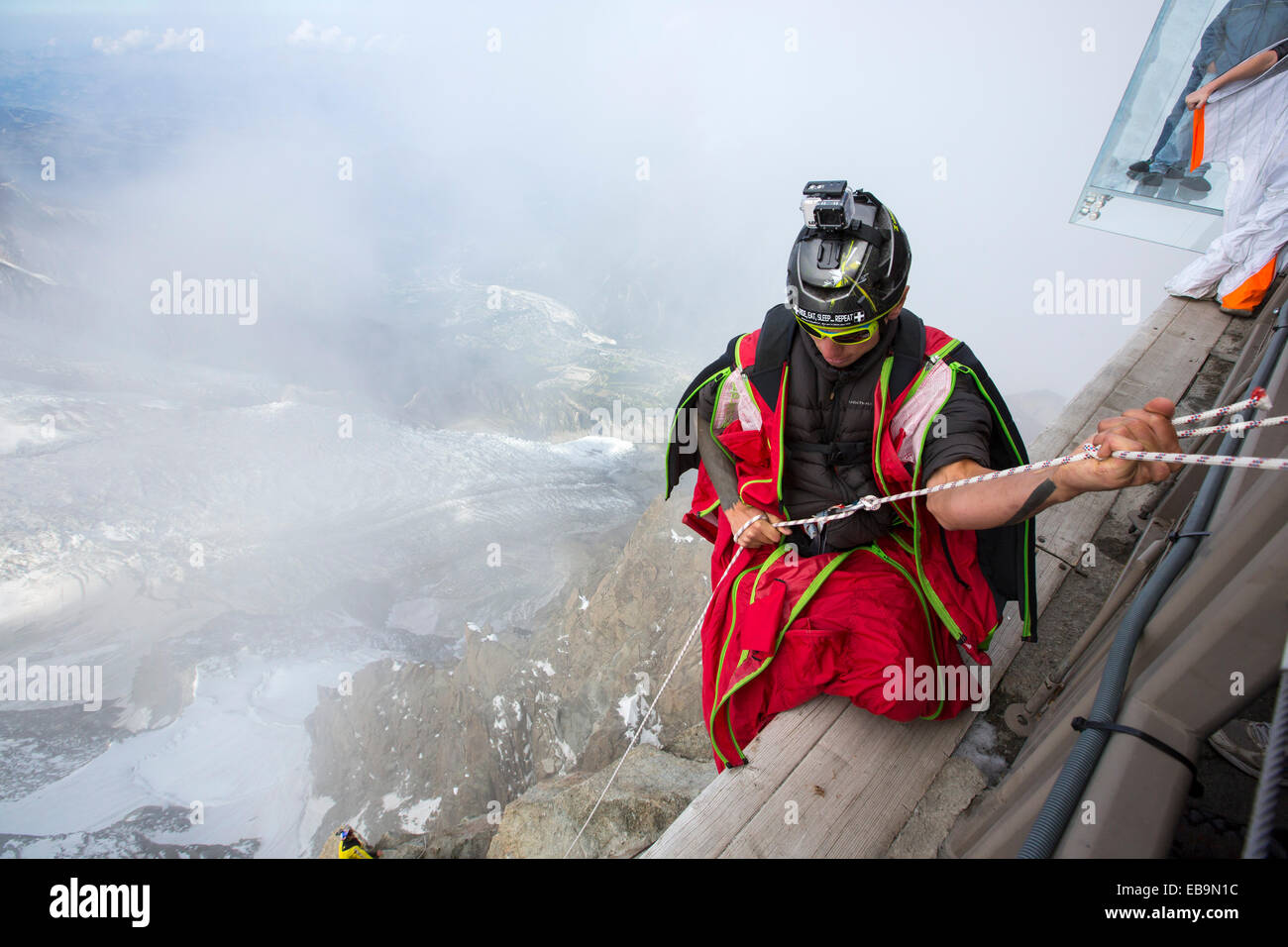 Ponticelli di base indossando wing suites preparare per passare dall'Aiguille du Midi al di sopra di Chamonix, Francia, con i turisti in una gabbia di vetro sopra la voragine nel retro di massa. Foto Stock