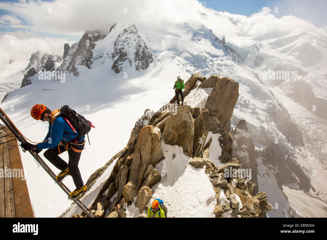 Mont Blanc dall'Aiguille du Midi al di sopra di Chamonix, Francia, con gli alpinisti sul Cosmétiques Arete, salendo la scala per accedere alla stazione della funivia. Foto Stock