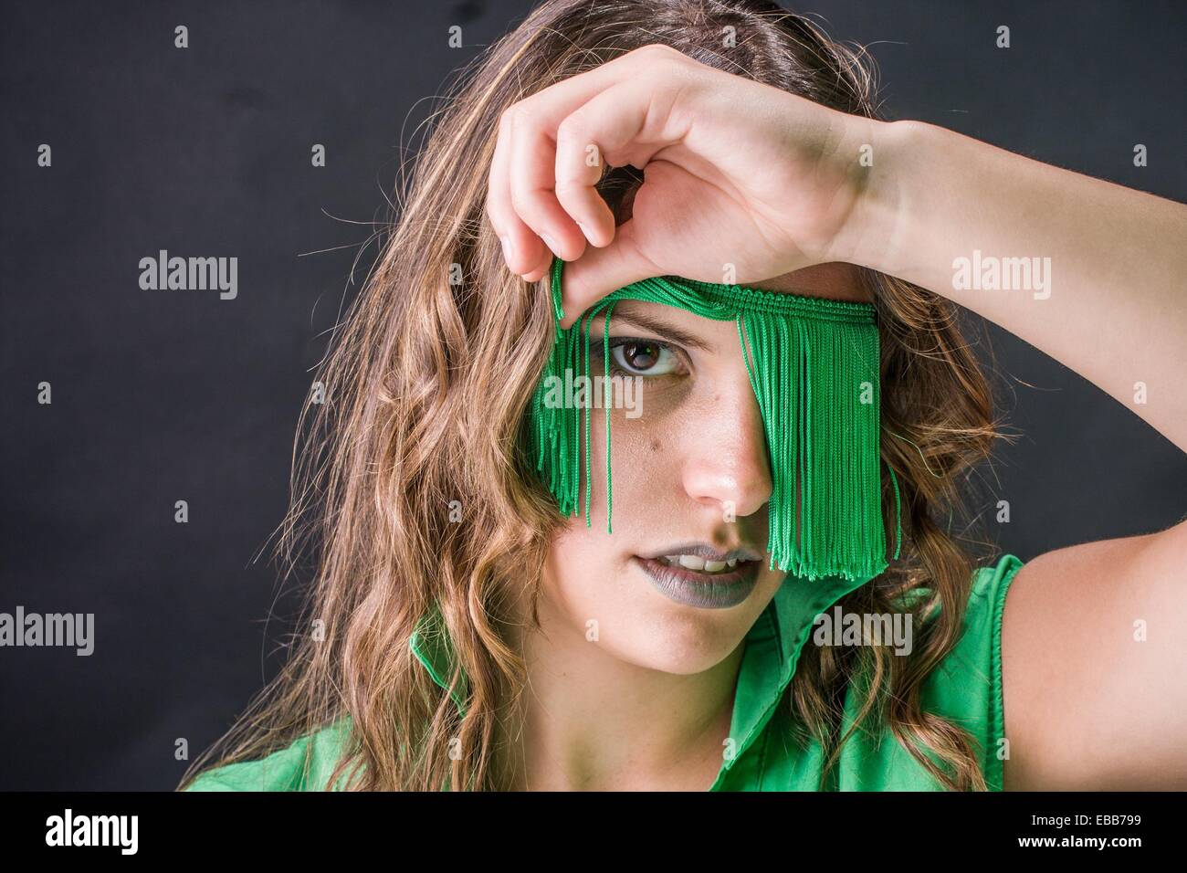 Giovane donna che guarda fuori da una benda di frange di colore verde Foto Stock
